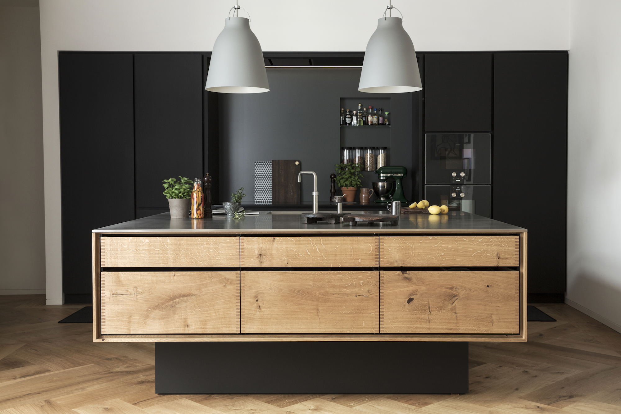 wood-island-kitchen-gray-pendant-lights-black-backsplash-denmark-garde-Hvalsoe
